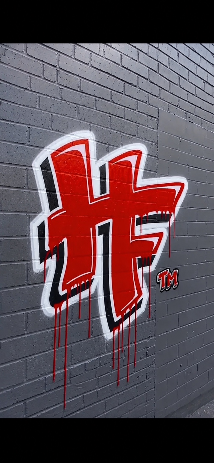 Red HF graffiti artwork painted on a gray brick wall